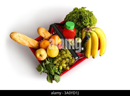 Roter Warenkorb voller frischer Produkte und Baguette auf weißem Hintergrund. Draufsicht Stockfoto