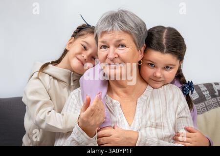 Porträt einer glücklichen Großmutter mit Kindern, die sich auf dem Sofa umarmen Stockfoto