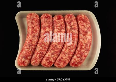 Eine Packung ungekochter italienischer Würstchen auf einem weißen Kunststofftablett vor dunklem Hintergrund. Stockfoto