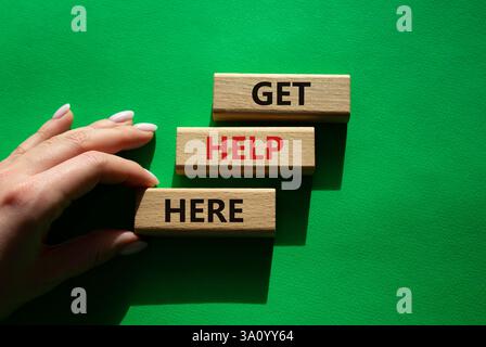 Hilfesymbol. Holzklötze mit Worten, hier Hilfe. Schöner grüner Hintergrund. Geschäftsmann Hand. Business and Get Help HERE Konzept. Kopie s Stockfoto
