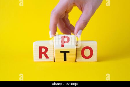RPO vs. RTO-Symbol. Geschäftsmann-Hand dreht Holzwürfel und ändert das Wort RTO in RPO. Schöner gelber Hintergrund. Geschäftskonzept. Kopierbereich Stockfoto