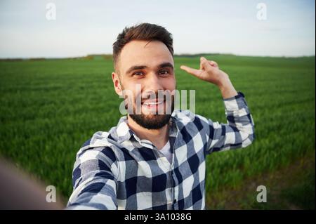 Selfie machen. Ein hübscher junger Mann ist auf dem Ackerfeld. Stockfoto