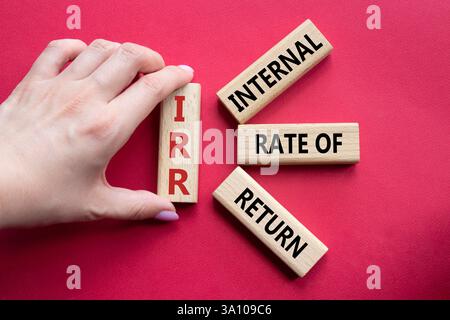 IRR - Internal Rate of Return symbol. Concept word IRR on wooden cubes. Businessman hand. Beautiful red background. Business and IRR concept. Copy spa Stockfoto