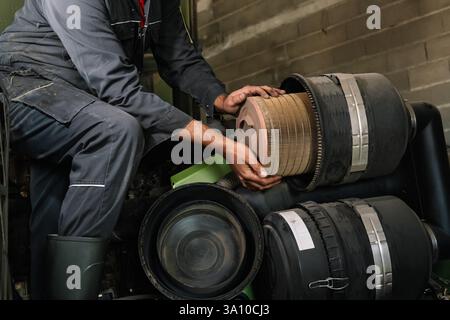 Kaukasischer Landwirt hält während der Wartung in der Garage einen verschmutzten Luftfilter des Traktormotors Stockfoto