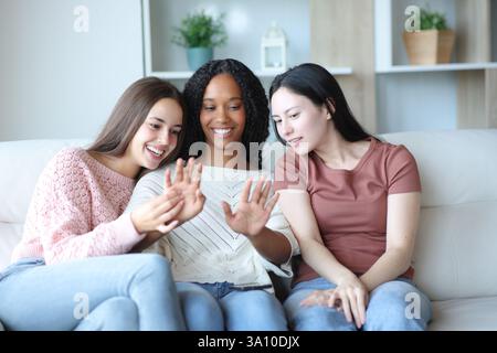 Drei glückliche Frauen, die zu Hause auf einer Couch sitzen Stockfoto