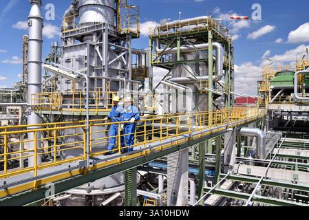 Gruppe von Arbeitnehmern Berufsausrüstung in einer Erdölraffinerie - moderne Gebäude und Industrieanlagen für die Brennstoff- und Gasproduktion Stockfoto