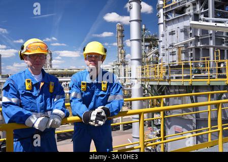 Gruppe von Arbeitnehmern Berufsausrüstung in einer Erdölraffinerie - moderne Gebäude und Industrieanlagen für die Brennstoff- und Gasproduktion - Close Stockfoto