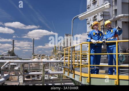 Gruppe von Arbeitnehmern Berufsausrüstung in einer Erdölraffinerie - moderne Gebäude und Industrieanlagen für die Brennstoff- und Gasproduktion Stockfoto
