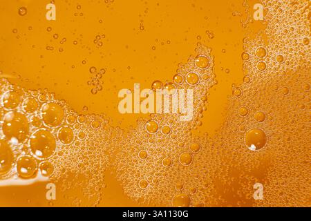 Abstrakter orangefarbener flüssiger Hintergrund mit Blasen auf der Oberfläche Pflanzenöl von oben Stockfoto