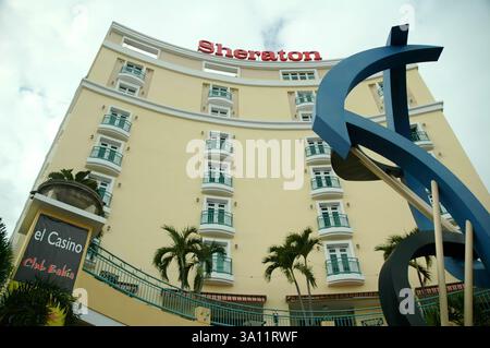 02/13/2020 - San Juan, Puerto Rico: Sheraton Hotel in Puerto Rico mit einer geschwungenen Fassade mit mehreren Balkonen und Geländern. Eine große blaue Form Stockfoto