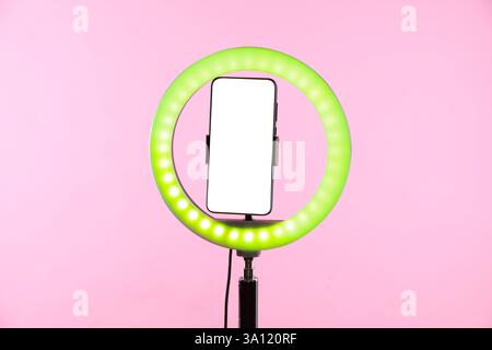 Ringlampe mit Smartphone auf rosa Hintergrund Stockfoto