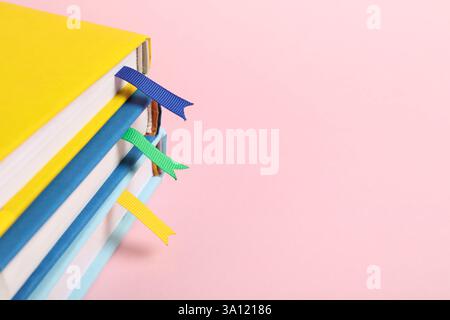 Bücher mit Lesezeichen auf rosafarbenem Hintergrund, Großaufnahme. Leerzeichen für Text Stockfoto