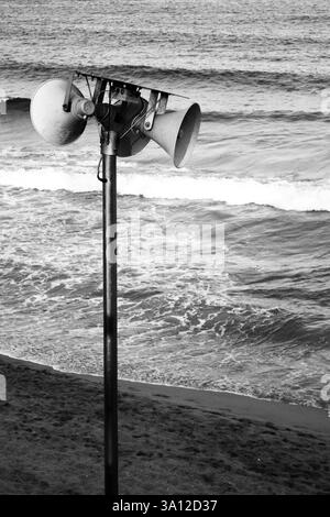 Konische Lautsprecher an einem Pol vor dem Hintergrund der Meereswellen. Schwarz-weiß, Form und Kontrast, natürliche Landschaft. Stockfoto