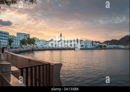 Der Sonnenuntergang wirft goldene Farbtöne über der Muttrah Corniche in Maskat, Oman, wo die Uferpromenade auf den ruhigen Golf von Oman trifft. Die Szene erfasst das c Stockfoto
