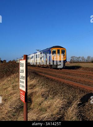 Unter dem breiten blauen Himmel von West Lancashire nähert sich ein Zug der Northern Railway auf der Strecke von Southport nach Wigan Stockfoto