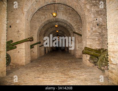 Bogengang mit verwitterten Kanonen im Gjirokaster Castle: Albaniens dauerhafte Festung aus der osmanischen Ära, die das Erbe des Balkans durch die Zeit verkörpert Stockfoto