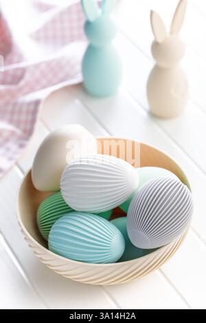 Osterdekoration. Bunte Eier in einer Schüssel auf einem weißen Tisch. Stockfoto