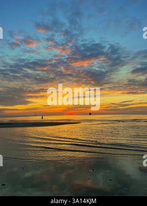 Ruhiger Sonnenuntergang über dem Meer, mit goldenen Tönen und sanften Reflexen auf dem Wasser. Ein friedlicher Moment der Ruhe und Fernweh. Stockfoto