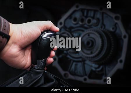 Nahaufnahme des Handschaltens des Fahrers, des Gangschalthebels und des Getriebes mit verschwommenen Metallgängen auf dunklem Hintergrund, Konzept für Autoteile. Stockfoto