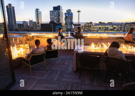 Die Leute trinken Cocktails mit Blick auf die Skyline von Seattle und Space Needle mit dem Puget Sound und den Olympic Mountains in der Ferne. Stockfoto