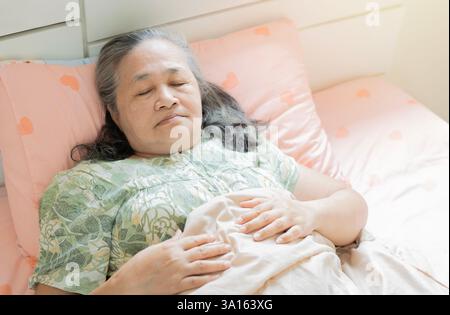Nahaufnahme einer ruhigen Seniorin, die auf der Seite liegend und friedlich in einem bequemen Bett, einem weichen Kissen mit Kopierraum schläft. Stockfoto