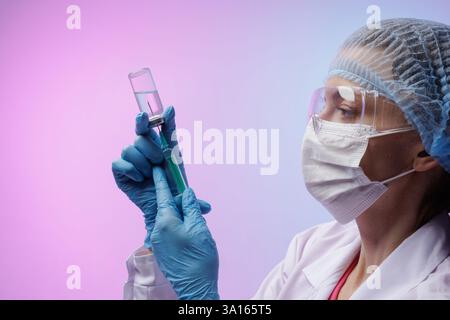 Weibliche Ärztin in Schutzmaske und Handschuhen Füllspritze mit Impfstoff aus Glasfläschchen, medizinische Injektionsvorbereitung. Das Konzept der modernen Medizin Stockfoto