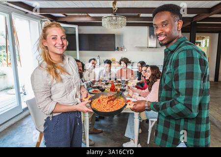 Verschiedene Freunde genießen ein köstliches Spaghetti-Abendessen zusammen, feiern Freundschaft und teilen eine Mahlzeit in einer modernen Umgebung Stockfoto
