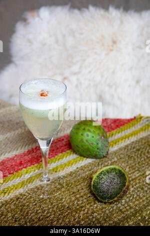 Peru, Andenkordillera, Colca-Tal, Colca-Schlucht, Tarapoto, ein Glas Pisco Sour auf einem Tisch mit peruanischer Wolldecke in Puqio, einem Campinghotel mit Blick auf die Anden Stockfoto