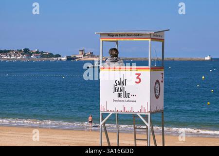 Frankreich, Pyrenäen Atlantiques, Saint Jean de Luz, Rettungsschwimmer auf seinem Hochstuhl, der über den großen Strand, Ciboure und die Festung Socoa im Hintergrund wacht Stockfoto