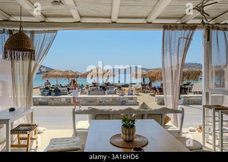 IOS, Griechenland - 5. September 2024 : Blick auf eine schöne weiß getünchte Strandbar mit Liegestühlen und Sonnenschirmen am Gialos Strand in iOS Griechenland Stockfoto