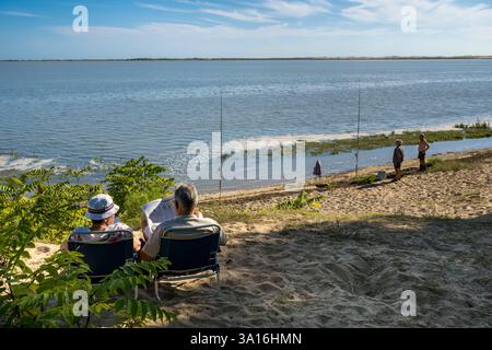 Frankreich, Charente-Maritime, Royan, Les Mathes, Angler am Rande der Bucht von Bonne Anse bei Flut und Lesen der Zeitung Stockfoto