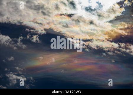 Himmelsfoto mit einer faszinierenden Perlwolke unter weißen Wolken, hinter denen die Sonne verborgen ist. Das intensive Licht erzeugt ein abstraktes Gemälde Stockfoto