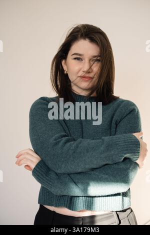 Frau in blauem Pullover mit gekreuzten Armen, weiches natürliches Licht Stockfoto