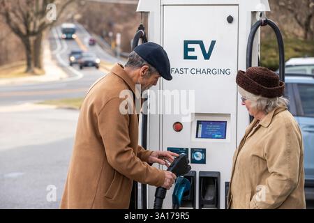 Ein Ehemann hilft seiner Frau, die EV-Ladestation zu benutzen Stockfoto