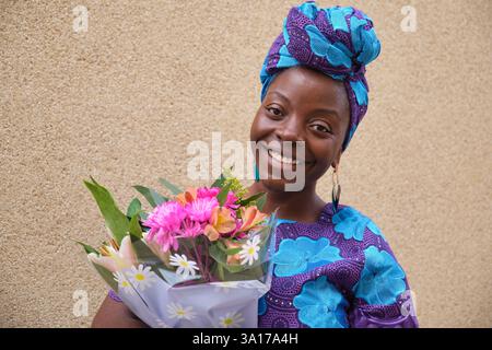 Junge afroamerikanische Frau, die Blumenstrauß hält und lächelt Stockfoto