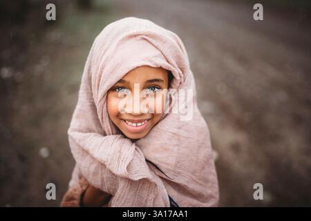 Schwarzes Mädchen grüne Augen Schal auf Kopf außerhalb der Landschaft regnerischen Tag Stockfoto