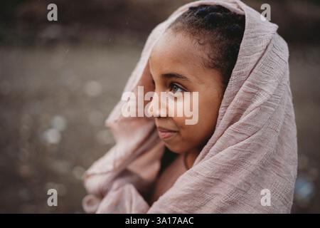 Schönes schwarzes Mädchen mit Schal auf dem Kopf draußen auf dem Land Stockfoto