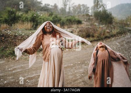 Glückliches schwarzes Mädchen, der Regen fühlt Freude, schwangere Mutter die Zunge rauszustechen Stockfoto