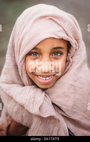 Schwarzes Mädchen grüne Augen Schal auf Kopf außerhalb der Landschaft regnerischen Tag Stockfoto
