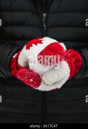 Nahaufnahme von Händen, die Kanadas Handschuhe tragen, die einen Schneeball machen. Stockfoto