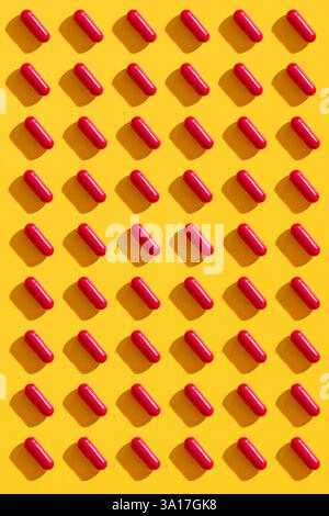 Rote Pillen in Reihen auf gelbem Hintergrund, kreatives Layout. Medizin, Gesundheitskonzept Stockfoto