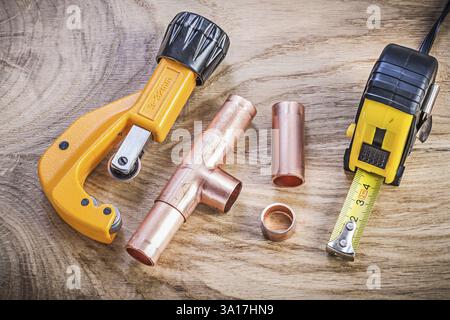 Kupfer-Wasserrohrschneider-Steckverbinder Bandmaß auf Holzplatte Sanitär-Messing-Konzept Stockfoto