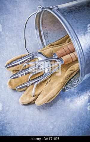Galvanisierte Eimer Metall Rechen Kelle Gabel Leder Sicherheitshandschuhe auf metallischem Hintergrund Gartenkonzept Stockfoto