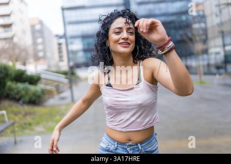 Sorglose junge lateinfrau, die im Freien in der städtischen Umgebung tanzen und Freude und Freiheit ausdrücken kann Stockfoto