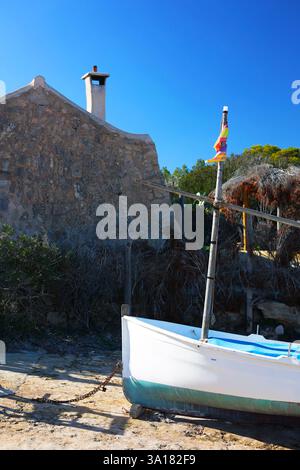 Altes verlassenes Boot in der Nähe eines Hauses am Meer. Altes verlassenes Boot mit Flagge in der Nähe des Hauses am Meer. Altes Tonsteinhaus. Weißes Boot mit Mast Stockfoto