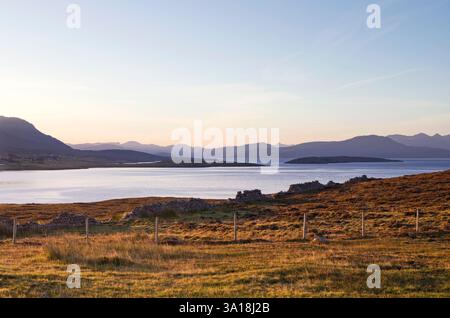 Atmosphärischer Sonnenaufgang im September an der Küste von Polbain, Coigach, mit einer alten Trockenmauer, die sich vom ruhigen blauen Wasser der Badentarbet Bay abhebt Stockfoto