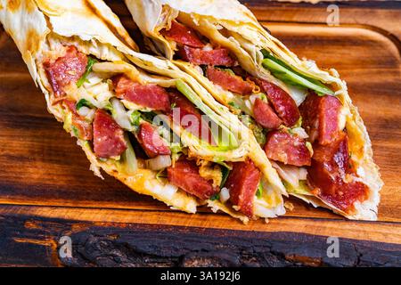 Es wird eine frisch zubereitete Wrap präsentiert, die mit lebhaftem Gemüse und herzhaftem Fleisch voller Farben strotzt. Die Kombination aus Aromen und Texturen lädt zum Deinen ein Stockfoto