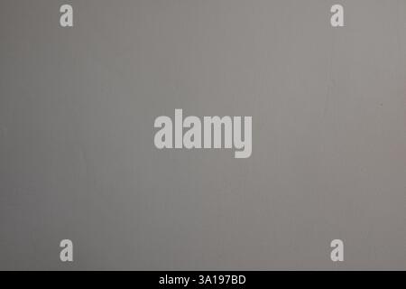 Eine graue Wand mit einem weißen Fleck drauf. Die Wand ist sehr schlicht und hat keine Dekoration Stockfoto