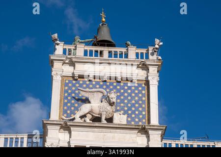 Nahaufnahme des Markusturms mit dem geflügelten Löwen von Venedig vor blauem sternenbedeckten Hintergrund und den bronzenen Mauren, die auf die Glocke schlagen Stockfoto