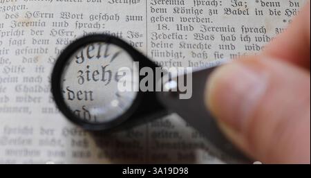 Eine Lupe bewegt sich über den Text eines alten Buches Stockfoto